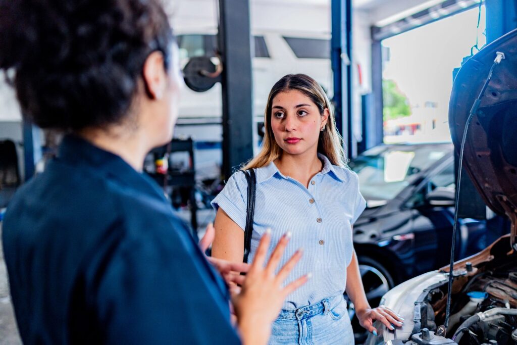 Young customer woman talking to mechanic at auto repair shop